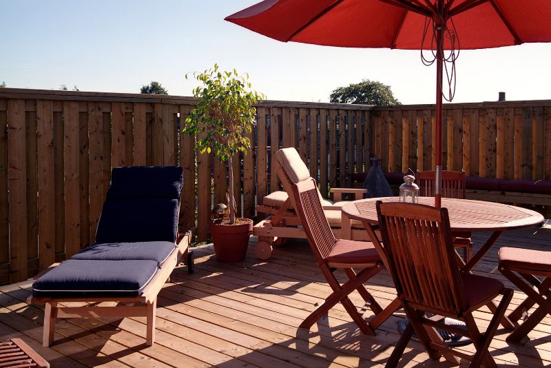 timber decking with timber railing, outdoor dining table & chairs and a lounge chair