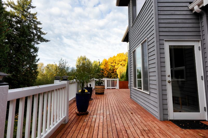 modern family home with a timber deck with white railing and potted plants