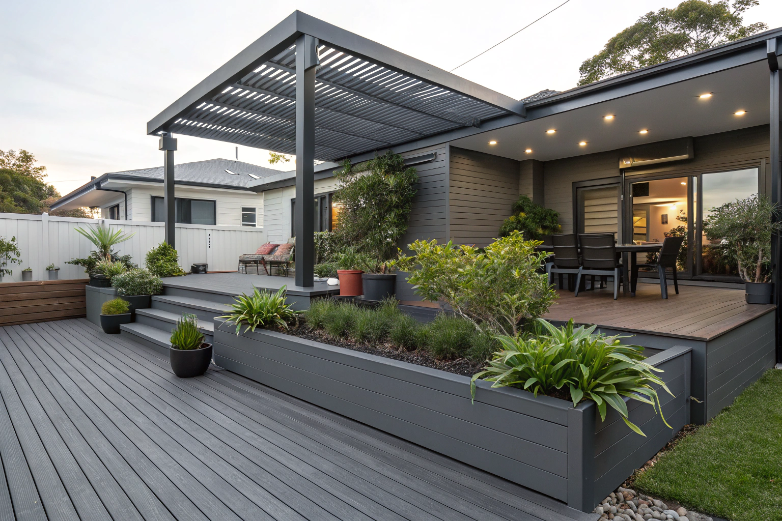 Charcoal grey composite deck with built-in planter boxes and an aluminium louvre pergola